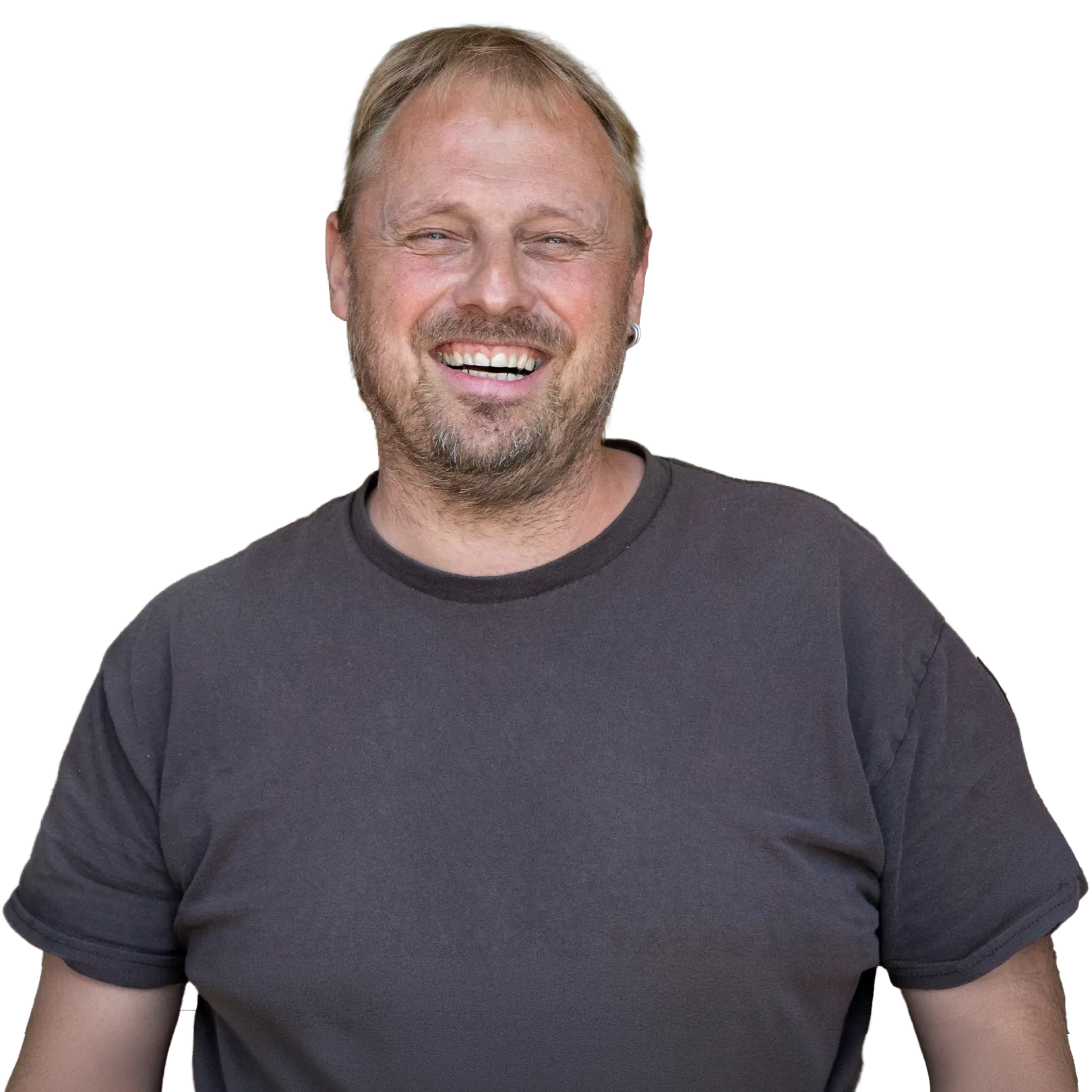 Person lächelt in die Kamera, trägt dunkles T-Shirt vor schwarzem Hintergrund